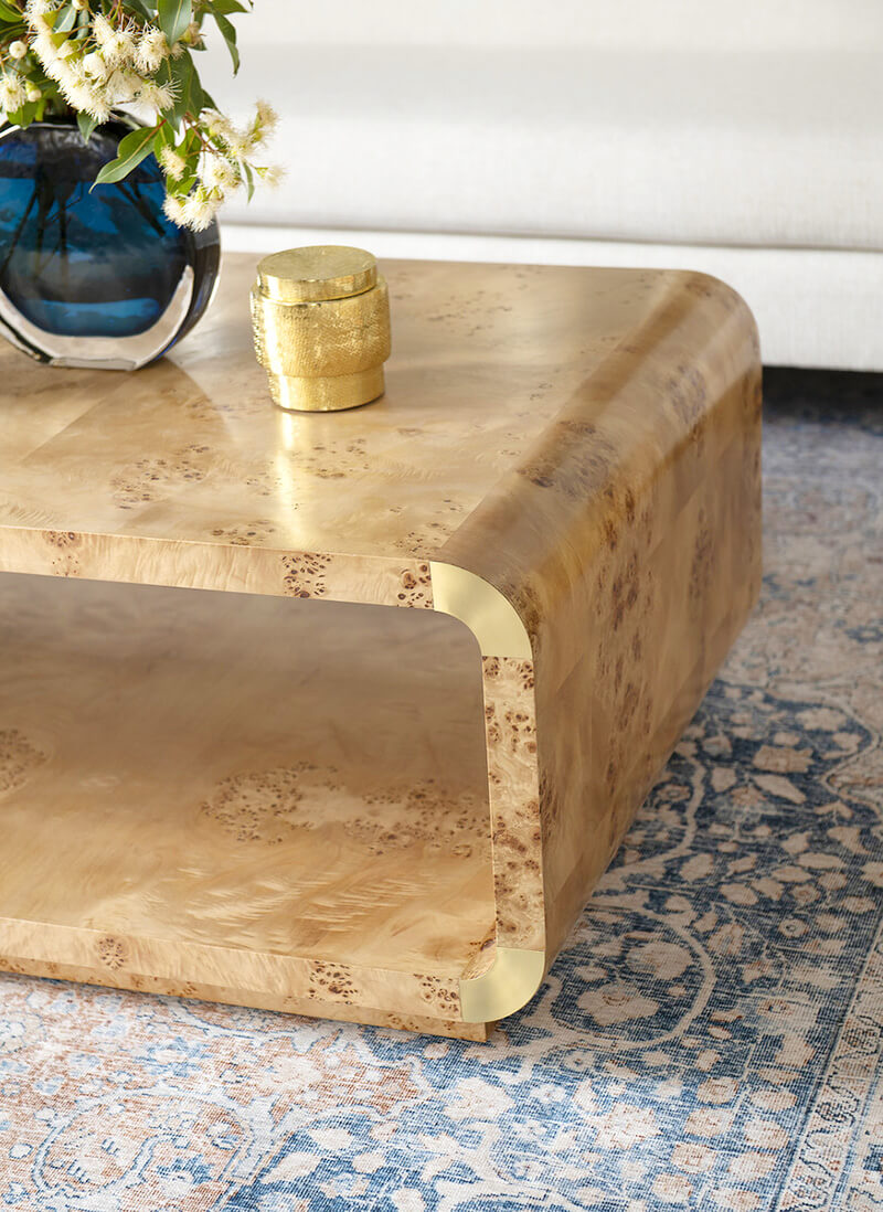 a coffee table with a burl-wood veneer and gold accents